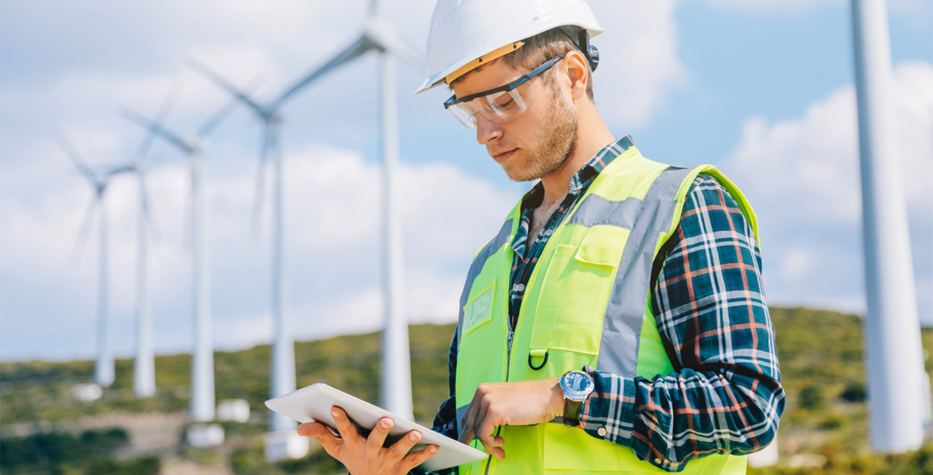 Engineer reading documents, wind turbines in the background (photo)